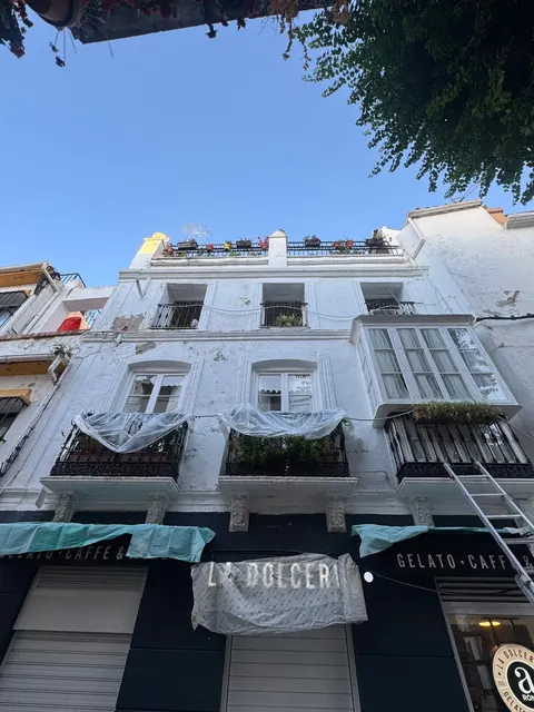 Fachada de una casa de dos plantas antes de pintar, con la pintura vieja amarillenta y manchada