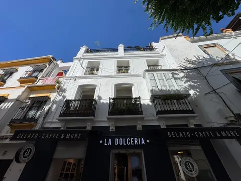 La misma fachada recién pintada de blanco, con la escalera apoyada y el pintor trabajando junto al limonero